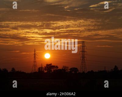 The sun setting behind electrical power lines. Quebec,Canada Stock Photo