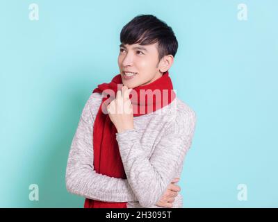 Handsome young man wearing a red scarf, thinking and looking above.Isolated on blue background. Stock Photo