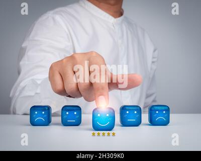 Customer service evaluation, feedback, rating, client experience and satisfaction survey concepts. Businessman's hand pointing the happy smile face ic Stock Photo