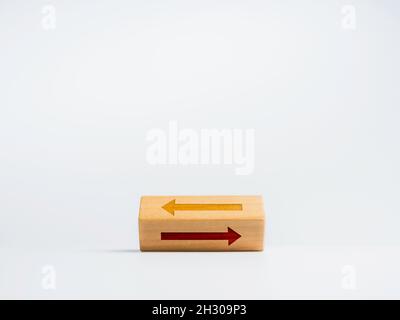 Flipping wooden block with two different arrows icon moving opposite way on white background. Choosing the correct pathway between left, right. Decisi Stock Photo