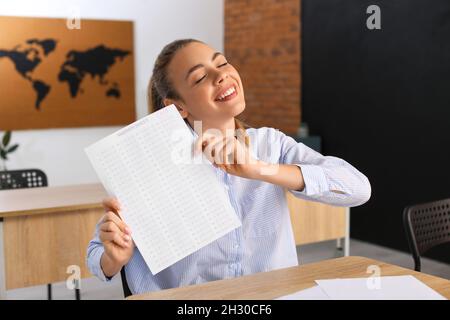 Happy student with answer sheet for school test in classroom Stock Photo