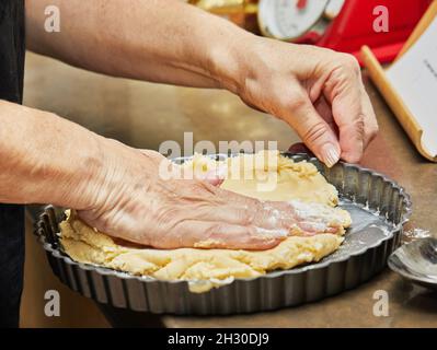 Chef prepares shortcrust cake and puts the dough into mold Stock Photo