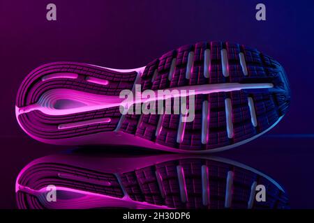 Sole of sport shoe with neon lights. Close up sneakers on dark background. Creative fashion style concept Stock Photo