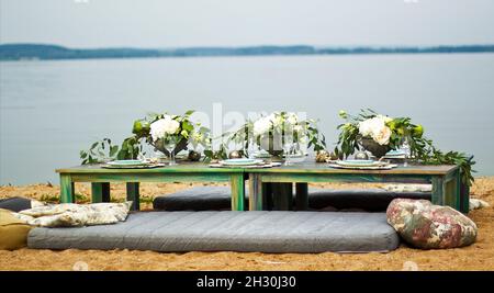 Beautifully served table on the sand by the sea Stock Photo