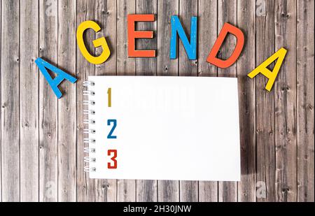 Agenda word made from wooden letters, next to notepad with place to write Stock Photo