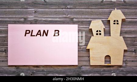 The text of plan B is written on a sticker, an icon of the house lies on a wooden table Stock Photo
