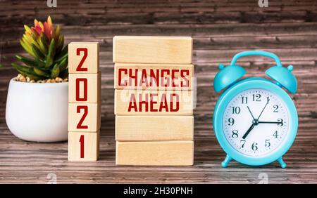 CHANGES AHEAD 2021 Concept written on wooden blocks and cubes Alarm clock and cactus stands on wooden table with change in 2021 concept. Stock Photo