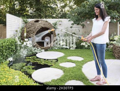 Sarah Keyser designer of the Living Landscapes: City Twitchers garden waters the display at the RHS Hampton Court Palace Flower Show 2015, Hampton Court Palace, London. Stock Photo