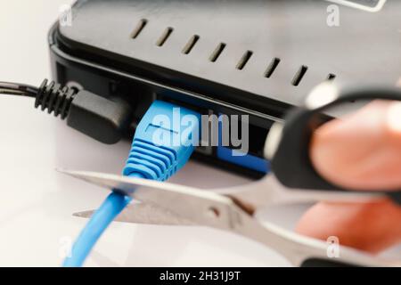 Scissors cutting LAN cable - no more internet. Stock Photo