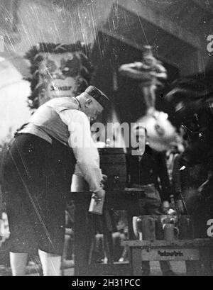 Ein Schankwirt zapft Bier während einer Karnevalsfeier, Deutsches Reich 1937.  A publican drawing beer during a carnival party, Germany 1937. Stock Photo