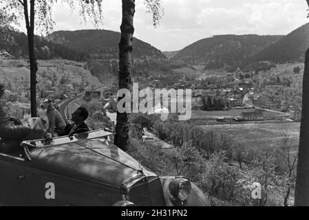 Ein junges Paar und ihr Hund bei einer Spazierfahrt mit dem Mercedes Cabrio in Hirsau im Nordschwarzwald, Deutschland 1930er Jahre. A young couple and their dog driving through Hirsau in the Northern Black Forest in a Mercedes convertible, Germany 1930s. Stock Photo