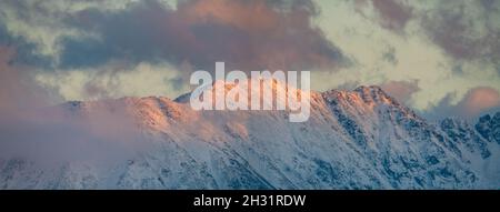 Panorama of snow-covered mountain peaks in the light of the setting sun Stock Photo
