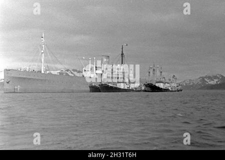 Das Fabrikschiff 'Jan Wellem' der deutschen Walfangflotte mit seinen Fangbooten im Eismeer der Antarktis, 1930er Jahre. Factory vessel 'Jan Wellem' of the German whaling fleet with its whaling boats heading an island in the Antarctic Sea, 1930s. Stock Photo