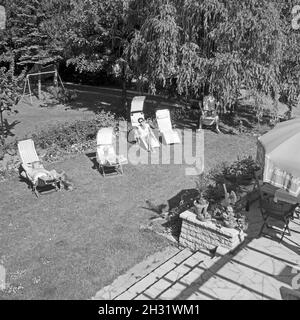 Friends in sunbeds sunbathing at the garden, Germany 1959 Stock Photo