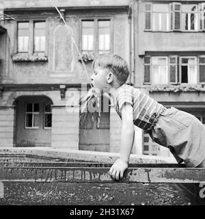 Ein Junge trinkt aus einem Marktbrunnen, Deutschland 1956. A boy drinking from a fountain on a market, Germany 1956. Stock Photo