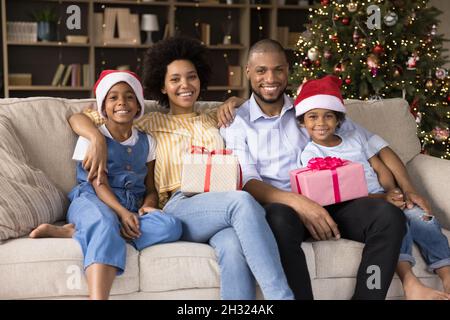 Happy african american family resting on sofa near Christmas tree. Stock Photo