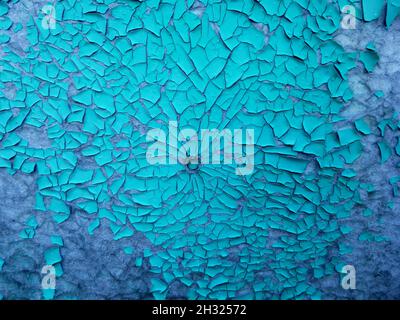 Blue peeling paint on the wall. Weathered rough painted surface with patterns of cracks and peeling. Texture for background and design. Stock Photo