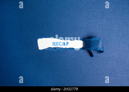 The text  RECAP appearing on white paper behind torn color paper. Stock Photo
