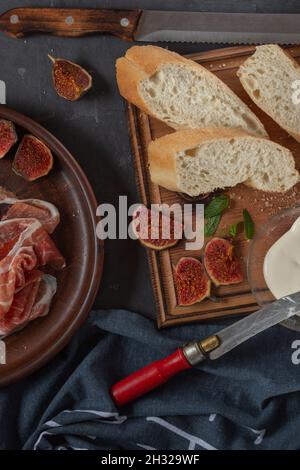 Jamon with figs and a baguette with cream cheese on the dining table, appetizer for wine, Spanish cooking. Stock Photo