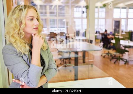 Young woman as a thoughtful businesswoman or trainee in open plan office Stock Photo