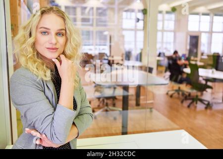 Young business woman as a self-confident trainee in training in an open-plan office Stock Photo