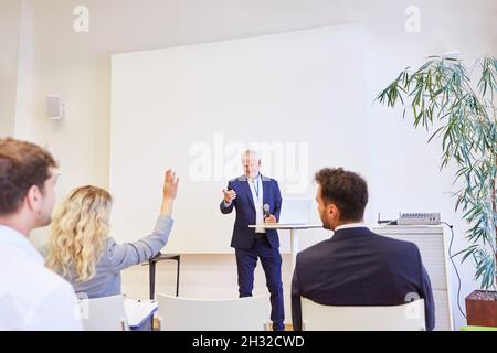 Speaker with microphone and audience giving a lecture in the lecture hall at a conference Stock Photo