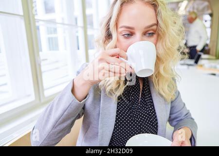 Young businesswoman is working on laptop computer and drinking a cup of coffee Stock Photo