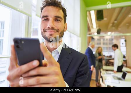 Young businessman uses smartphone app or sends a text message in the office Stock Photo