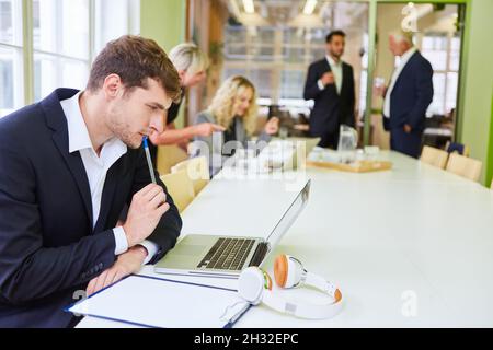 Young businessman in start-up meeting on laptop PC is thinking about a problem Stock Photo