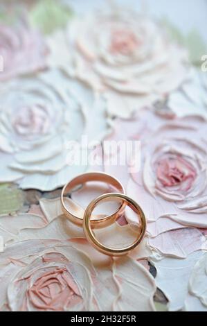 Classic wedding band set on the floral painted roses background with place for inscription. Invitation card. Gold wedding rings top view, flat lay. So Stock Photo