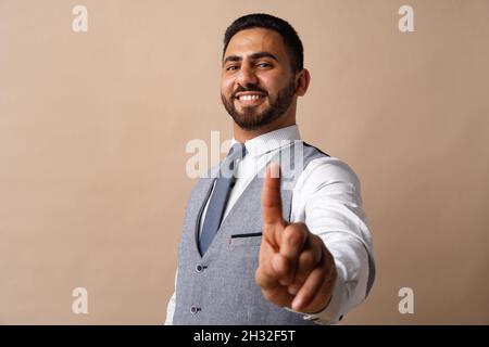 Young arabian businessman pointing finger to camera against beige background Stock Photo
