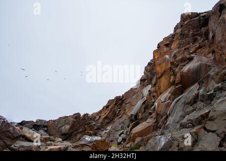 Stunning high rocky cliffs and sky | Amazing rock formations, cliff walls, with birds flying in the sky in the background Stock Photo