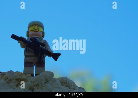 Chernihiv, Ukraine, July 13, 2021. Minifigure of a soldier girl with a sniper rifle in her hands against a blue sky background. Illustrative editorial Stock Photo