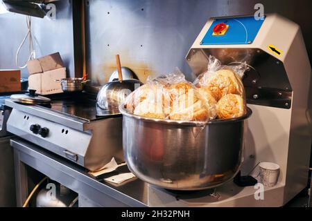 Professional dough kneader or kneading machine filled with hamburger buns in an industrial restaurant kitchen. Stock Photo