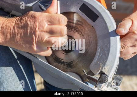 a man screws a saw blade with a hexagon on a circular miter saw for woodworking. Stock Photo