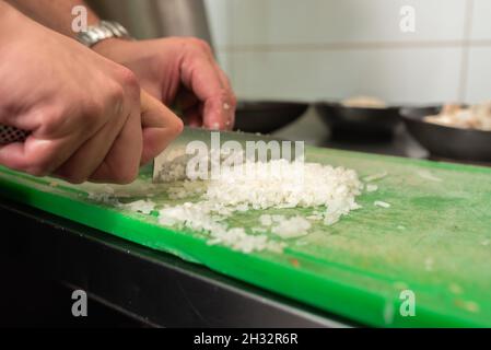 Chef cutting onion on a green cutting board Stock Photo