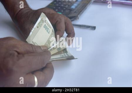 Senior aged Man hand counting Indian rupee note on table. High angle view. Close up. Stock Photo