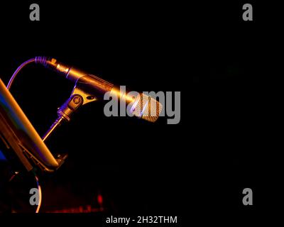 microphone on one side during a concert illuminated by orange colored lights, black background Stock Photo