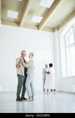 Two elderly couples enjoying dance with each other during lesson in dance studio Stock Photo