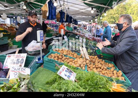 Greengrocer stall UK, selling vegetables to a customer in a mask during the COVID 19 pandemic, Salisbury market, Salisbury Wiltshire UK Stock Photo