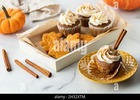 A tray of pumpkin spice cookies and cupcakes and one cupcake on a plate. Stock Photo