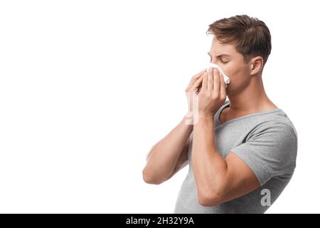 Millennial attractive caucasian guy suffering from first symptoms of flu and cold, runny nose, blows, feeling unwell, isolated on white background, fr Stock Photo