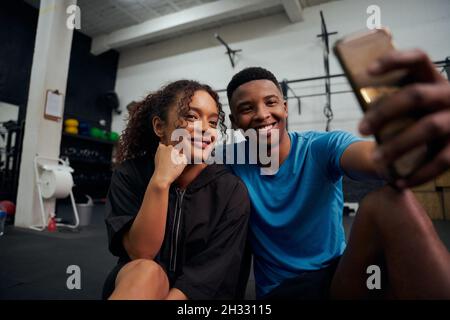 African American friends sitting on the floor and taking a photo together on the phone. African American couple taking a selfie together. High quality Stock Photo