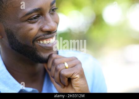 Happy pensive husband with black skin wearing wedding ring looking away Stock Photo