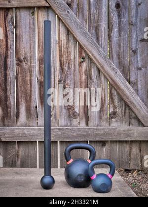 steel mace (macebell) and iron kettlebells against a rustic wooden gate in a backyard, home functional fitness concept using unconventional equipment Stock Photo