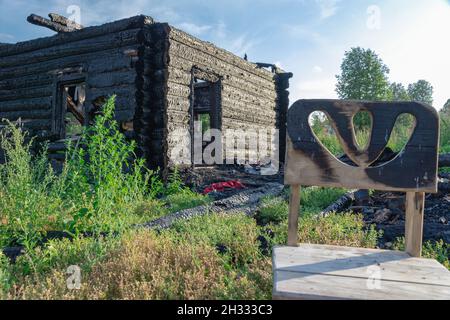Burnt old log house in the village on a bright summer day against the blue sky. Close-up Stock Photo