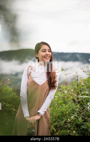 Cheerful young asian woman holding retro camera standing in the garden at the morning Stock Photo