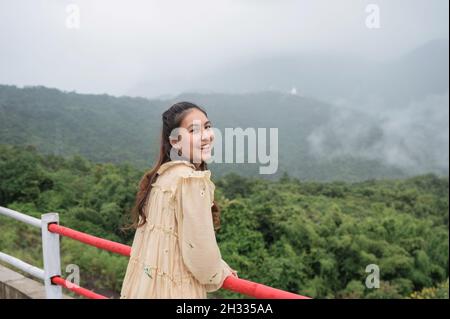 Cheerful asian woman smiling among the foggy mountain on rainy season in countryside Stock Photo