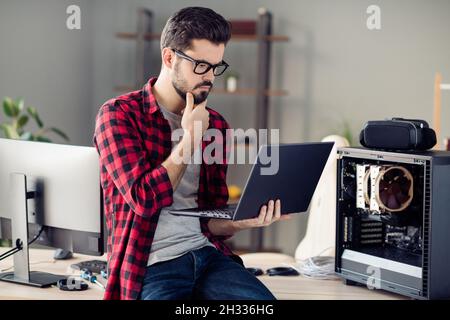 Portrait of attractive minded guy checking server error solving web network problem indoor at work place station Stock Photo