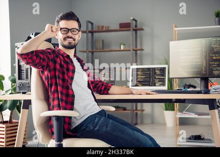 Profile side view portrait of attractive skilled cheerful guy writing code touching specs at work place station indoors Stock Photo
